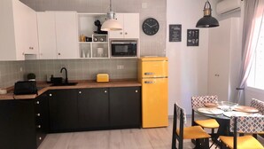 A modern kitchen with white cabinets, a yellow refrigerator, and a dining area with yellow chairs. - Holidays2Malaga Union Studio Renovated - High Speed WiFi (Málaga)