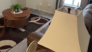 Un salon comprenant une table ronde, un canapé, une lampe et des éléments de décoration murale, notamment des horloges.