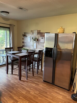 A kitchen with a stainless steel refrigerator, wooden dining table, chairs, and a window with curtains. - Great place to relax with family and friends (Daleville)