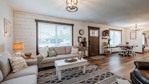 A spacious living room with a sofa, coffee table, and dining area. - The Fir Country Cottage (Philomath)