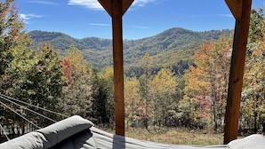 Una cama con vista a una cadena montañosa boscosa.