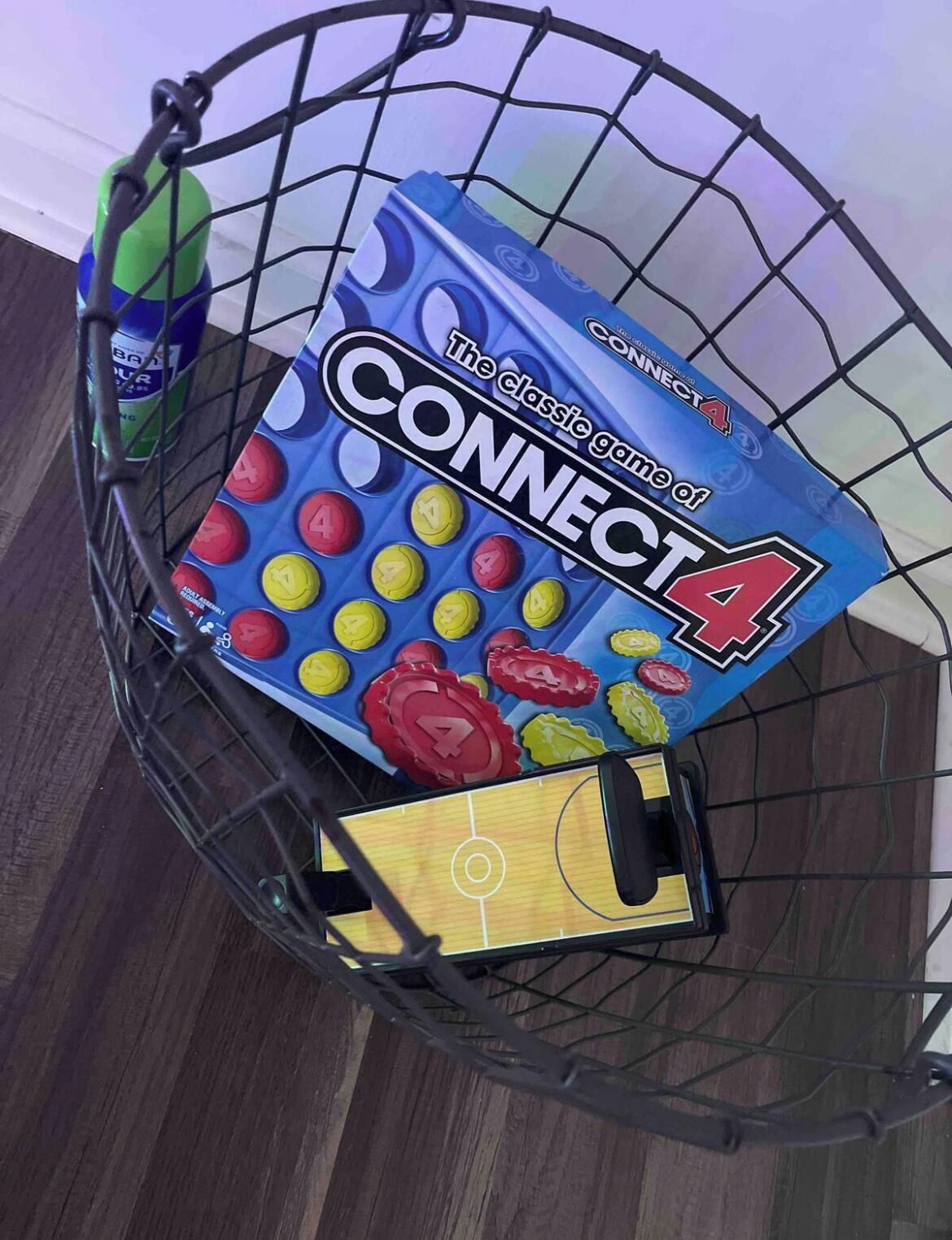 Un panier contenant une boîte de jeu de Connect 4 et un pion de jeu jaune.