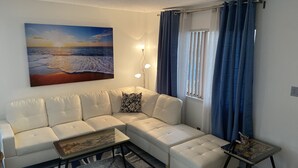 A modern living room with a white sectional sofa, a glass coffee table, and a patterned rug. - 2 Bedroom Home 20 Minutes From Everything! (North Las Vegas)