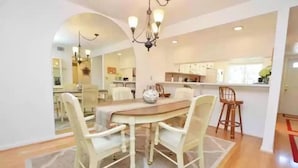 A dining area with a round table, four chairs, and a chandelier.