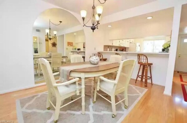 Uma sala de jantar com mesa redonda, quatro cadeiras e um lustre.