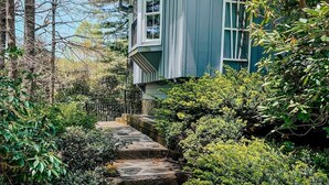 Escadaria de pedra que leva a uma casa rodeada por vegetação densa.