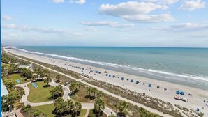 A beach with umbrellas, a walking path, and a view of the ocean. - Luxury Oceanfront 3 Bedroom Condo On The Boardwalk! (Myrtle Beach)