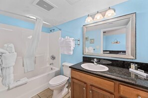 Un bagno con vasca, servizi igienici, lavabo e mobile lavabo.