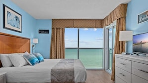 A hotel room with a bed, a TV, a desk, and a view of the ocean. - Luxury Oceanfront 3 Bedroom Condo On The Boardwalk! (Myrtle Beach)