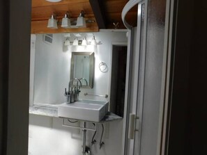 Ein Badezimmer mit weißem Waschbecken, Spiegel und drei Wandleuchten.