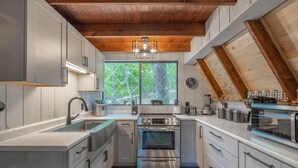 Une cuisine moderne dotée d’appareils électroménagers en acier inoxydable, de meubles blancs et d’un carrelage à motifs carrés.