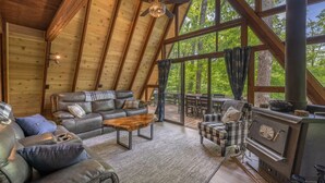 Une pièce chaleureuse de style loft, dotée d’une grande fenêtre, de poutres apparentes, d’une cheminée et de meubles en cuir.