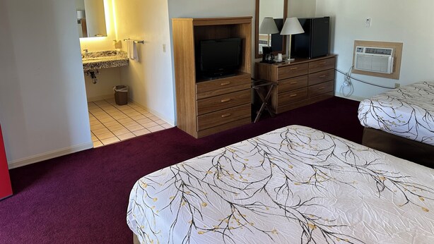 Ein Schlafzimmer mit Bett, Schminktisch, Fernseher und Spiegel.