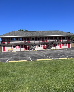 A two-story motel with a red and white facade, multiple balconies, and a parking lot.