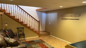 A living room with a staircase, a leather couch, a small table, and a patterned rug.