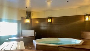 Ein Wellnessraum mit Whirlpool, Holzvertäfelung und Wandleuchten.
