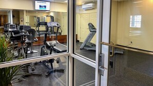Ein Fitnessraum mit Trainingsgeräten, Laufband und Spiegelwand.