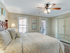 A bedroom with a bed, a ceiling fan, a window with blinds, and a door.