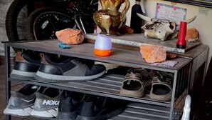 Ein Schuhregal mit mehreren Schuhpaaren, eine Vase und ein Schild auf einer Ablagefläche.