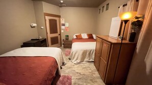 Ein Hotelzimmer mit zwei Betten, einem Schreibtisch, einem Schminktisch, einem Spiegel und einem Nachttisch.