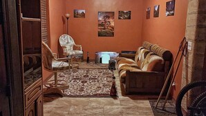 Ein gemütliches Wohnzimmer mit einer Couch, einem Sessel und einem gemusterten Teppich.