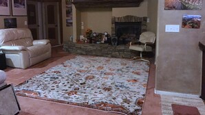 Ein Wohnzimmer mit Kamin, Steinwand und Deckenventilator.