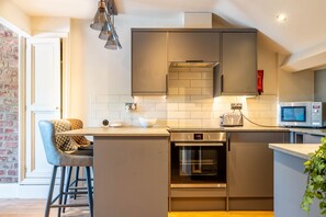 A modern kitchen with grey cabinets, a built-in oven, and a microwave.