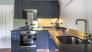 Una cucina moderna con mobili scuri, un lavello in acciaio inox e un forno integrato.