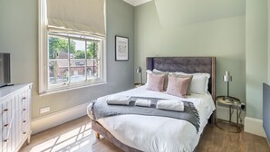 Una camera da letto con un letto, una finestra, un comodino e una lampada.