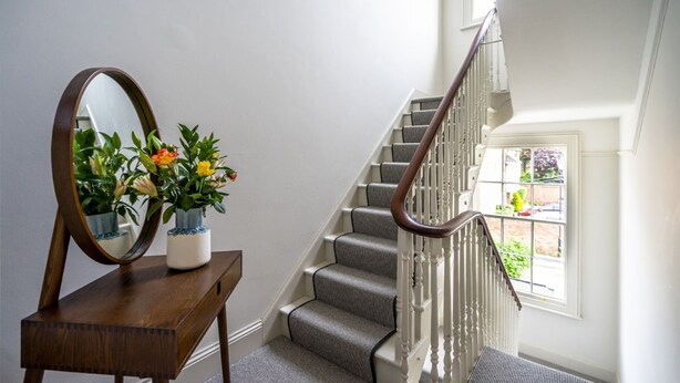 A staircase with a wooden handrail and carpeted steps, a wooden console table with a mirror and potted plants, and a window with a view of the outdoors. - A premium stay that sleeps 2 guests  in 1 bedroom (York)