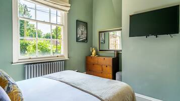 A bedroom with a bed, dresser, and a large window.