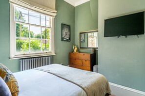 A bedroom with a bed, dresser, and a large window.