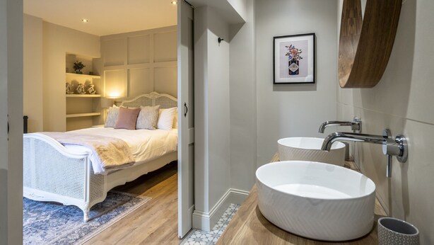 Una camera da letto moderna con un letto grande, comodini, un lavandino bianco e un quadro incorniciato appeso al muro.