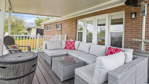A covered porch with a sectional sofa, wicker coffee table, and a barrel. - 5BR Mountainside Home w/ Views - Near SLC, Park City & Lagoon (Bountiful)