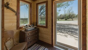 A wooden interior with a wooden chair, a dresser, and a window with a view of trees and a road. - Charming retreat close to downtown, hiking, lakes, 3 acre and private (Durango)