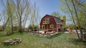 A red barn with a wooden deck and a fenced area with rocks. - Charming retreat close to downtown, hiking, lakes, 3 acre and private (Durango)