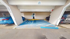 A parking garage with a guest parking area marked by a wheelchair accessibility symbol, a blue handicap parking space, and a sign indicating 'GUEST PARKING ONLY'.