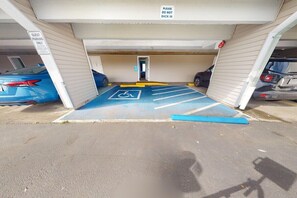 Een parkeergarage met een gastenparkeerplaats, gemarkeerd met een rolstoeltoegankelijkheids symbool, een blauwe parkeerplaats voor mindervaliden en een bord met de tekst 'ALLEEN VOOR GASTEN'.
