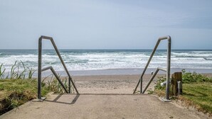 A beach entrance with metal railings and a concrete path leading to the ocean. - Accessible Oceanfront Studio With Kitchen & Pool (Lincoln City)