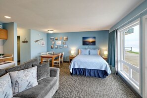 Een hotelkamer met een bed, een bank, een eettafel en uitzicht op het strand.