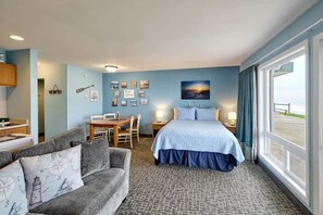 Une chambre d’hôtel avec un lit, un canapé, une table à manger et une grande fenêtre donnant sur un beau paysage.
