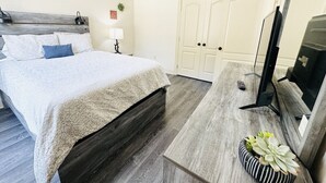 A bedroom with a bed, a desk with a computer, a TV, and a door. - Chateau 16, spacious townhouse in Tickfaw, LA (Tickfaw)