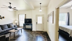 A living room with a sofa, coffee table, TV, and a door leading to another room. - Chateau 16, spacious townhouse in Tickfaw, LA (Tickfaw)