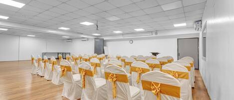 A large, well-lit room with rows of chairs covered in white fabric and yellow sashes, arranged for an event.