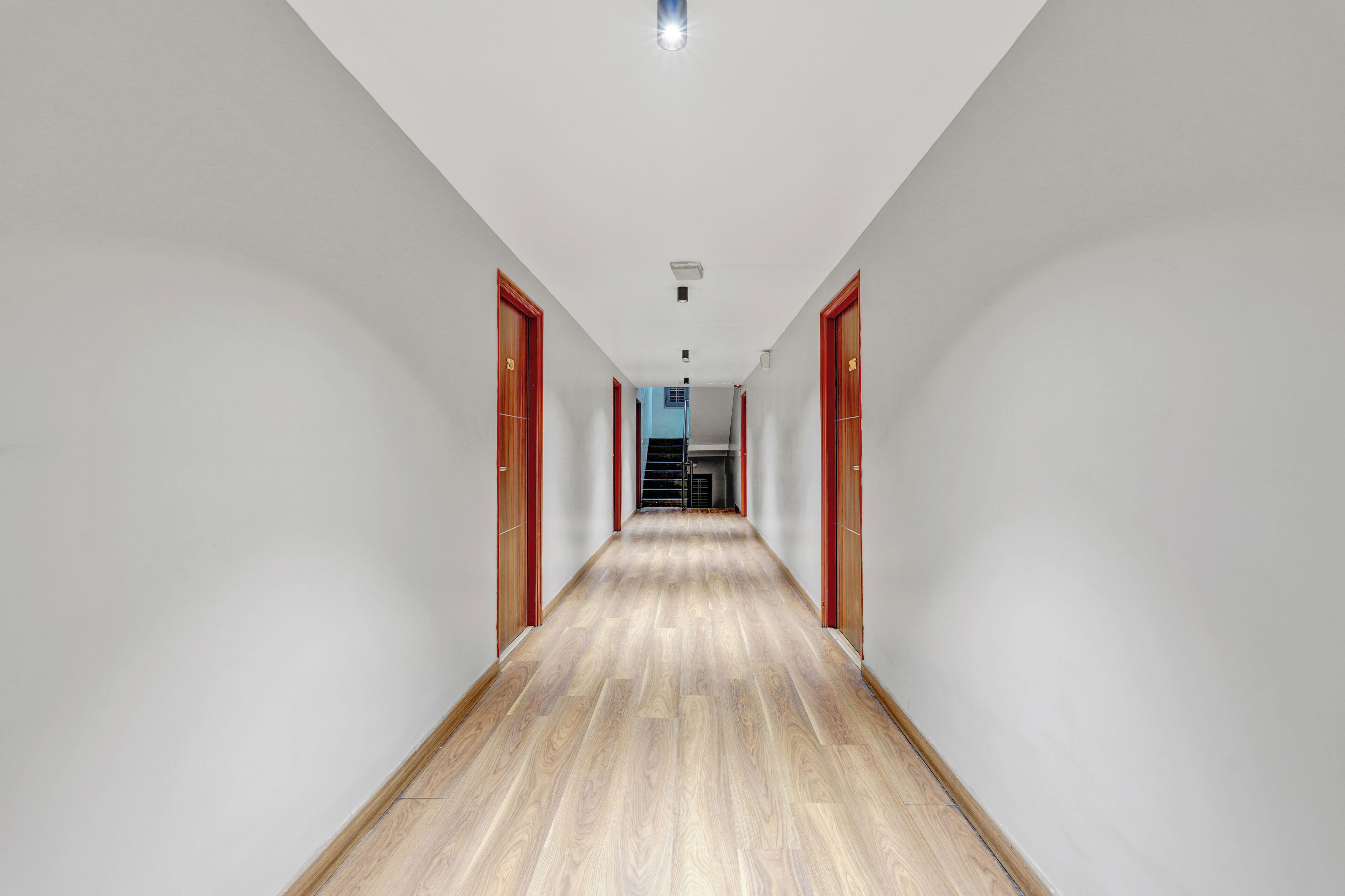 A long, narrow hallway with wooden flooring and white walls.