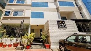 Um hotel de vários andares com fachada branca, janelas grandes e uma placa com a inscrição 'UPAR HOTELS'.