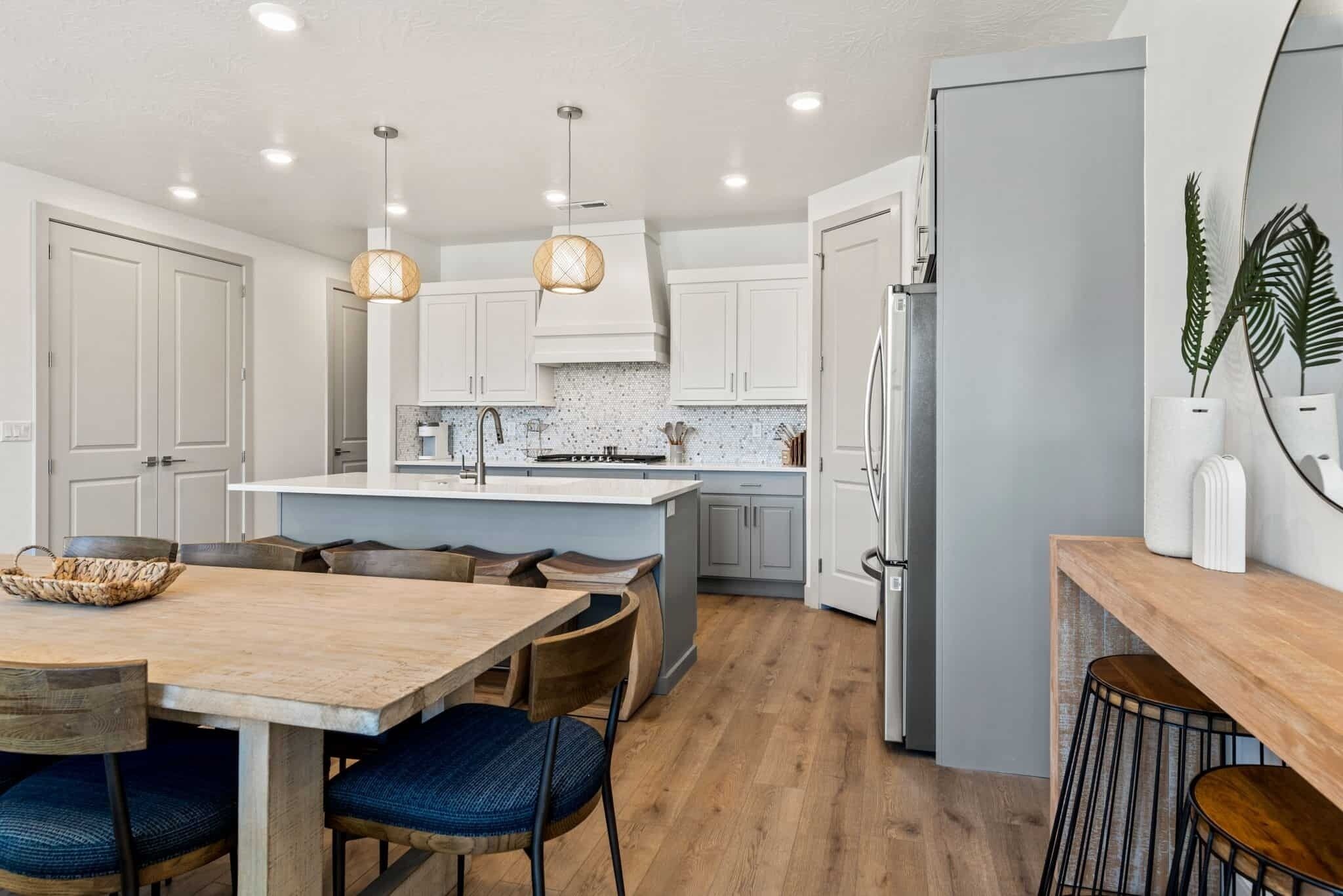 A modern kitchen with white cabinets, a central island, and pendant lighting.
