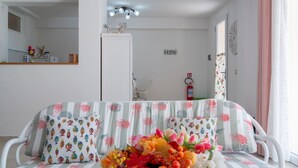 A room with a sofa, a mirror, a ceiling light, a door, and a wall-mounted clock. - Casetta Letizia in Portoferraio (Portoferraio)