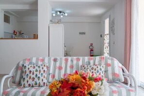 Una stanza con un divano, uno specchio, una lampada a soffitto, una porta e un orologio fissato al muro.