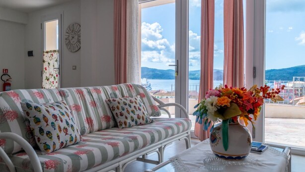 A room with a sofa, a vase with flowers, and a view of the sea. - Casetta Letizia in Portoferraio (Portoferraio)